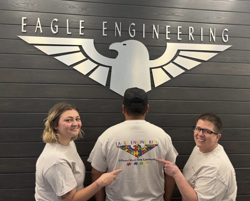 Eagle Engineering team members posing in front of the Eagle Engineering sign